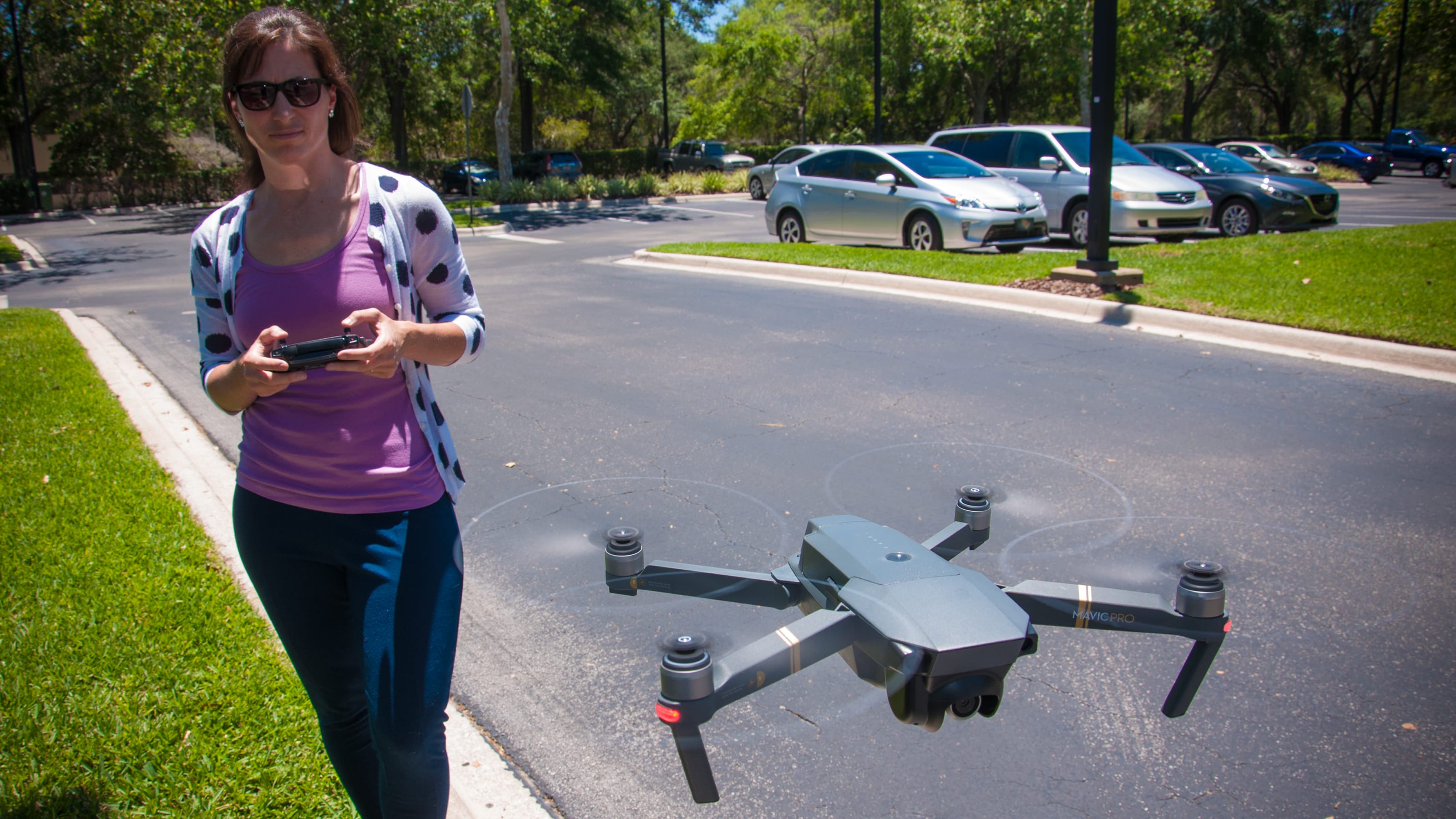 Woman flying a drone in a parking lot.