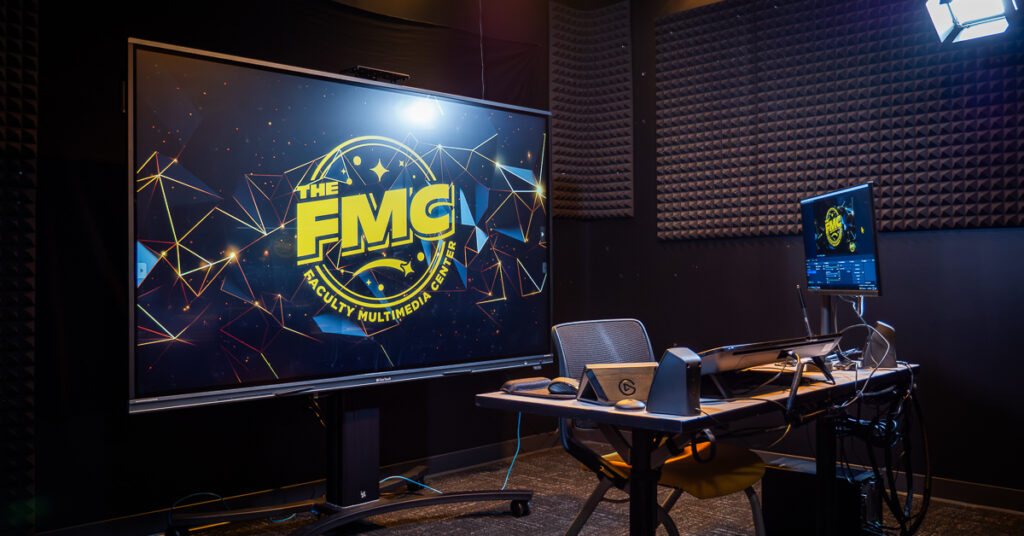 A livestreaming computer setup in front of a large TV screen at the UCF FMC.