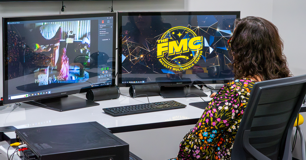 Woman sitting in front of two computer monitors editing a video